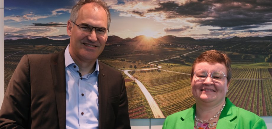 Landrat Dietmar Seefeldt und die neue Leitende staatliche Beamtin Sarina Hildmann stehen vor einem Landschaftsbild im Kreishaus.