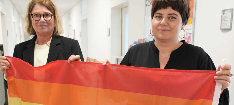 Lisa-Marie Trog, Gleichstellungsbeauftragte des Landkreises Germersheim und ihre Stellvertreterin Evi Julier, im Porträt. Sie halten eine Regenbogen-Flagge.