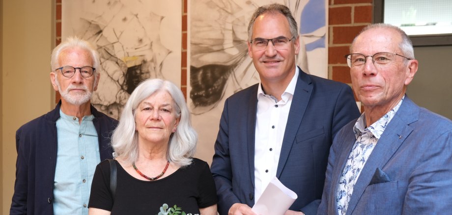 Die Künstler Rob Jansen und Carmen Stahlschmidt stehen mit Landrat Dietmar Seefeldt und Dr. Carlo Servatius, Vorsitzender der Eberhard und Barbara Linke Stiftung, vor einem Gemälde von Carmen Stahlschmidt.