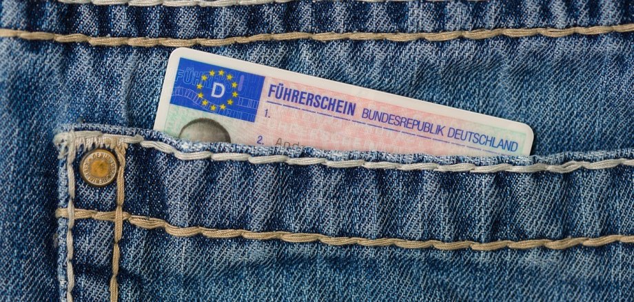 Der obere Teil eines Führerscheins schaut aus der Tasche einer Jeanshose heraus.